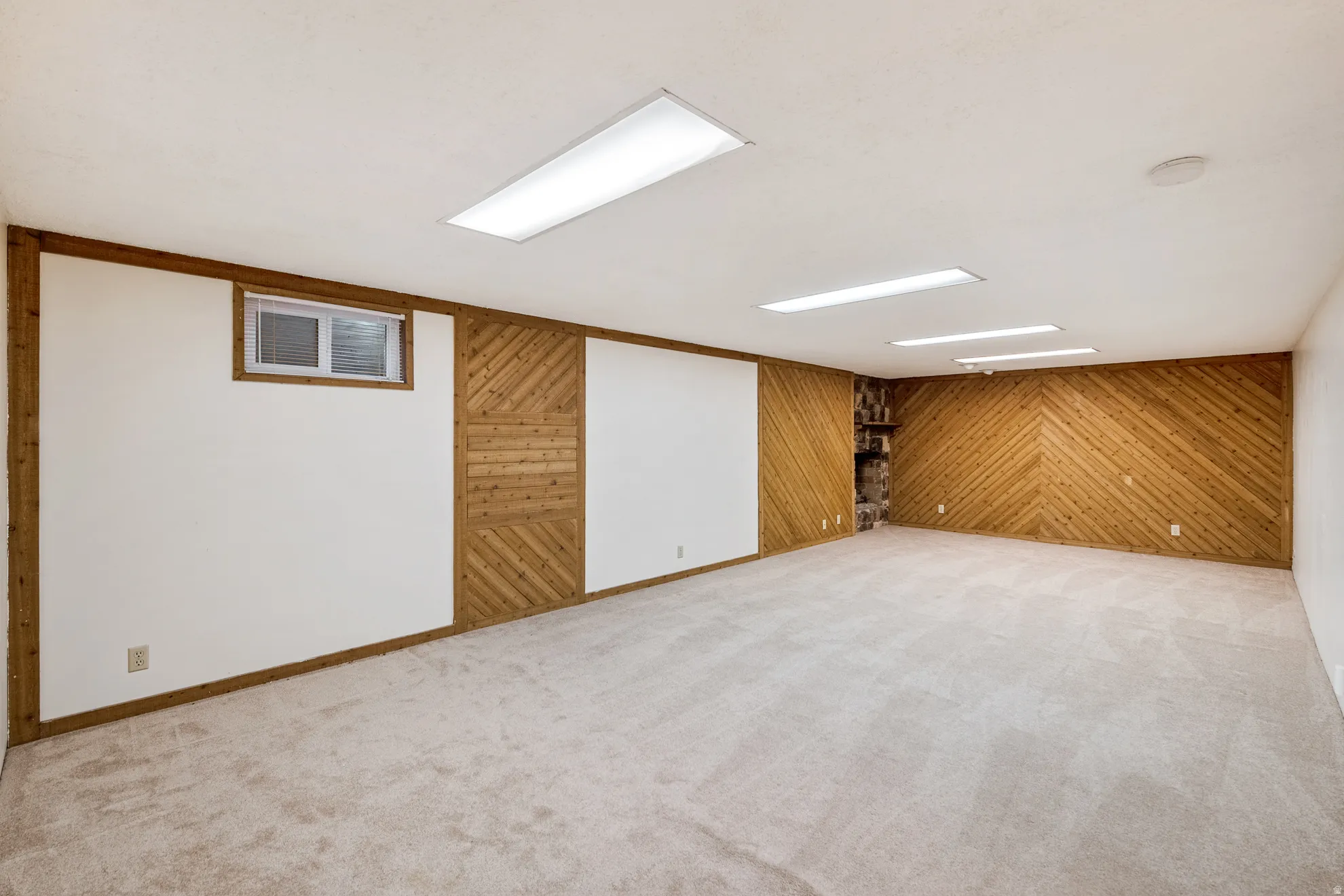 Expansive family room with neutral carpeting, fireplace, wood-paneled accent walls, built-in shelving, and recessed lighting
