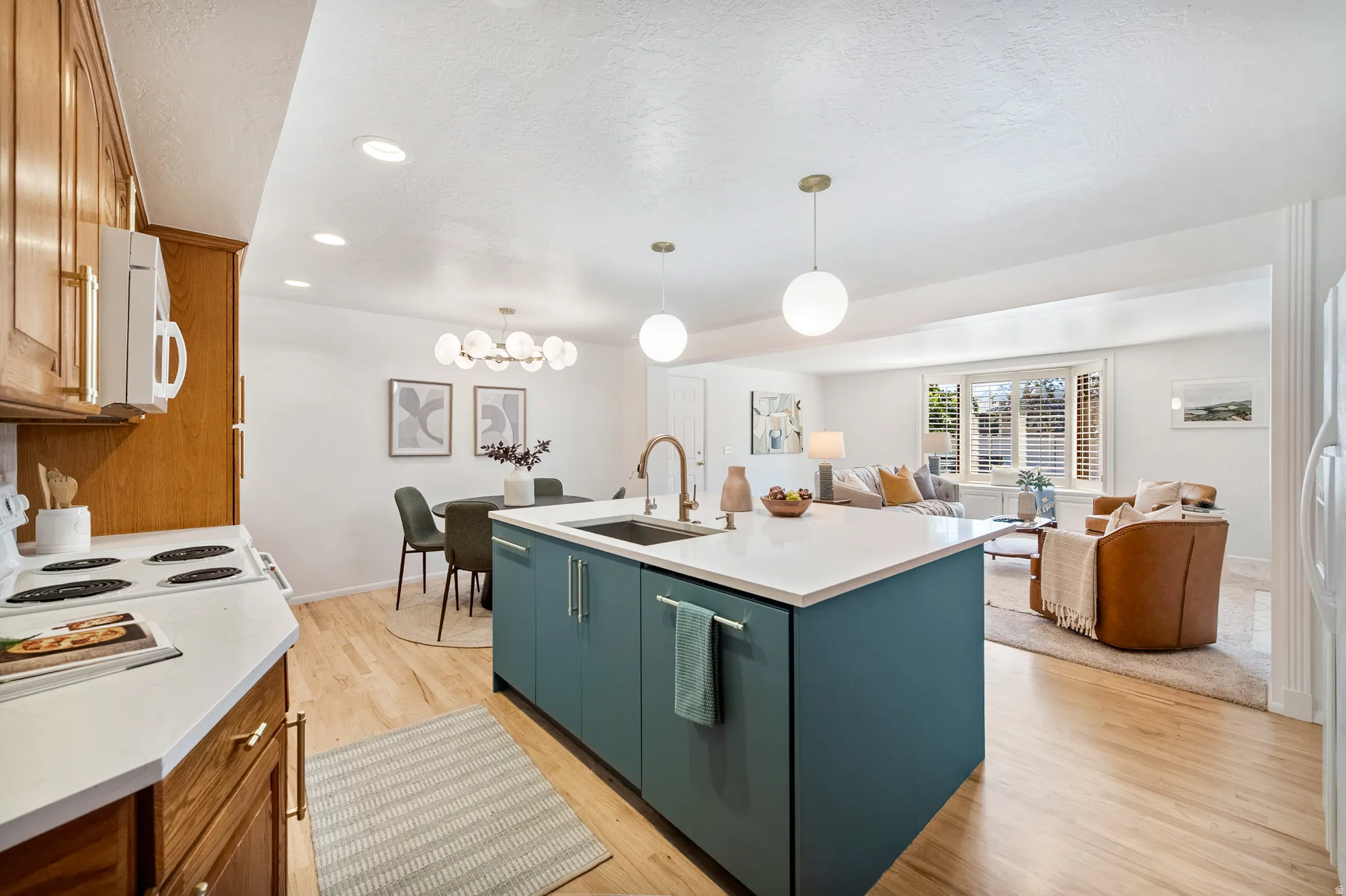 Open-concept kitchen featuring a central island with a sink, white countertops, and wood-finish flooring throughout