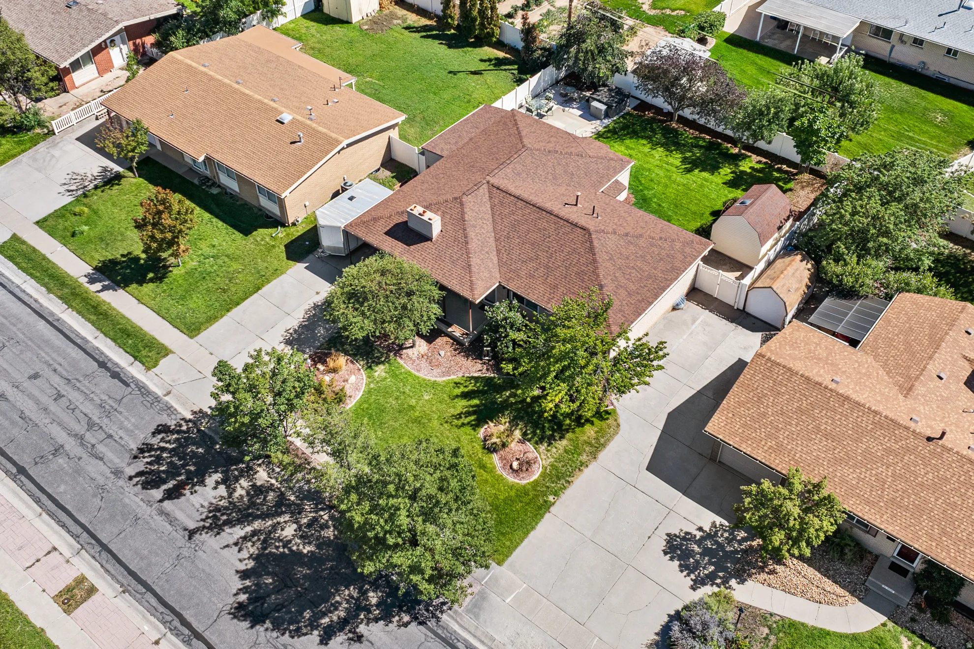 Expansive property featuring a brown shingle roof, concrete driveway, and mature landscaping