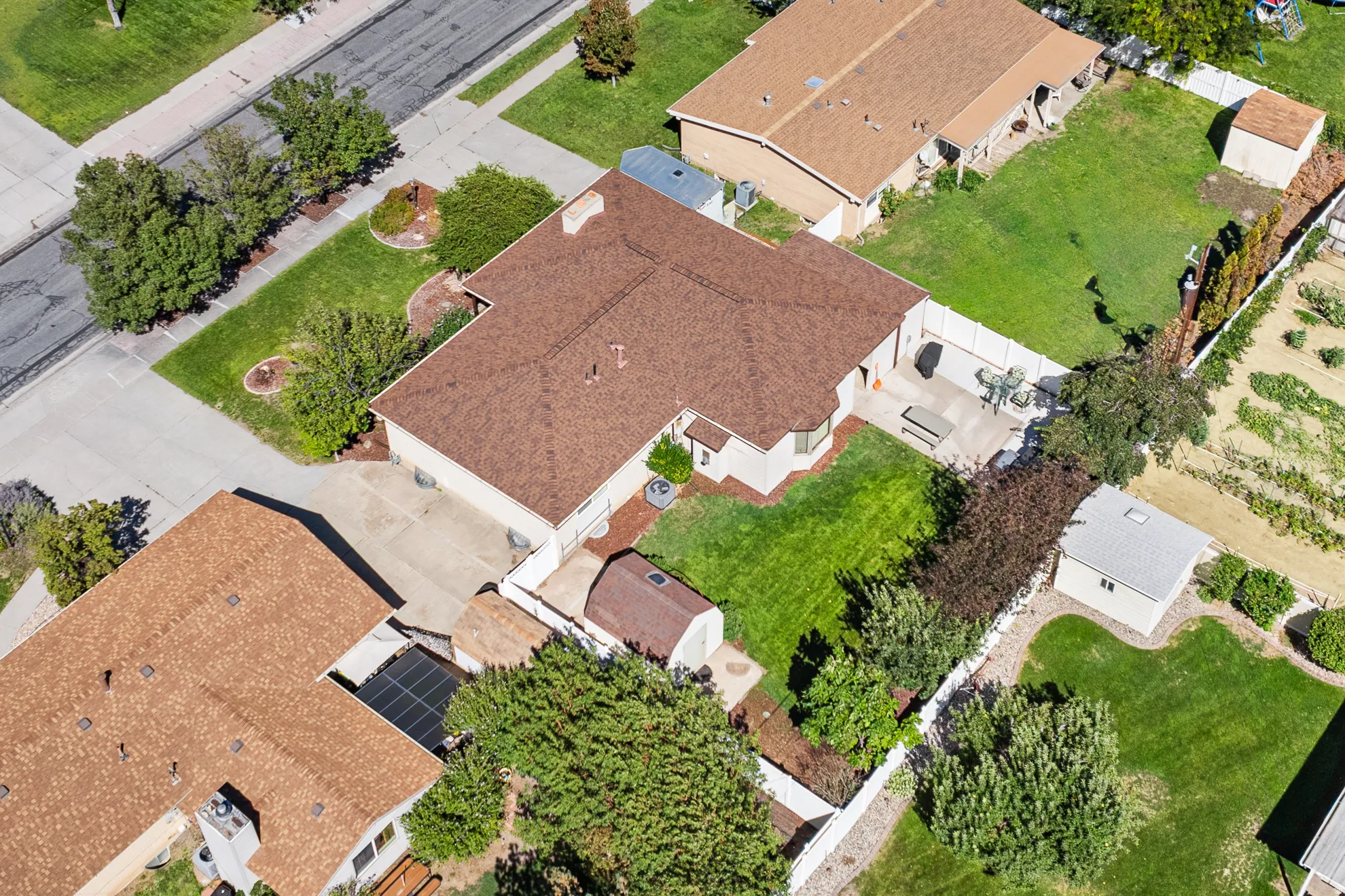 Expansive property featuring a brown shingle roof, concrete driveway, and a white privacy fence