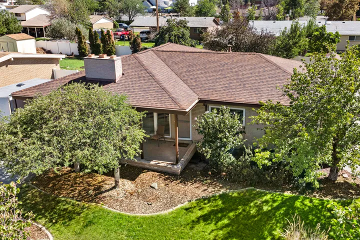 Pitched roof, brick chimney, covered porch, mature trees, manicured lawn
