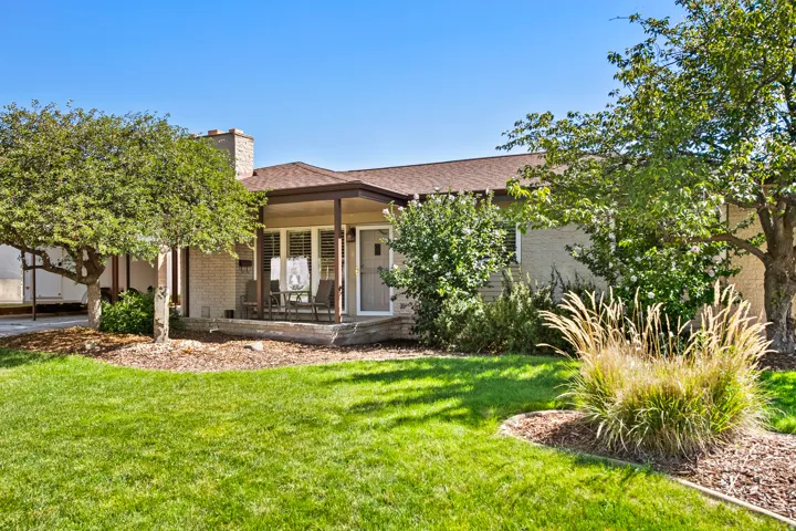 Brick exterior with a covered patio, extensive lawn, and mature landscaping