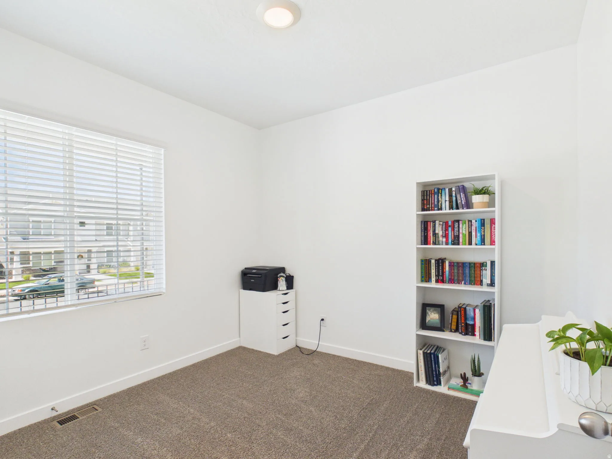 Recessed ceiling light, neutral wall paint, white window blinds, and carpeted flooring