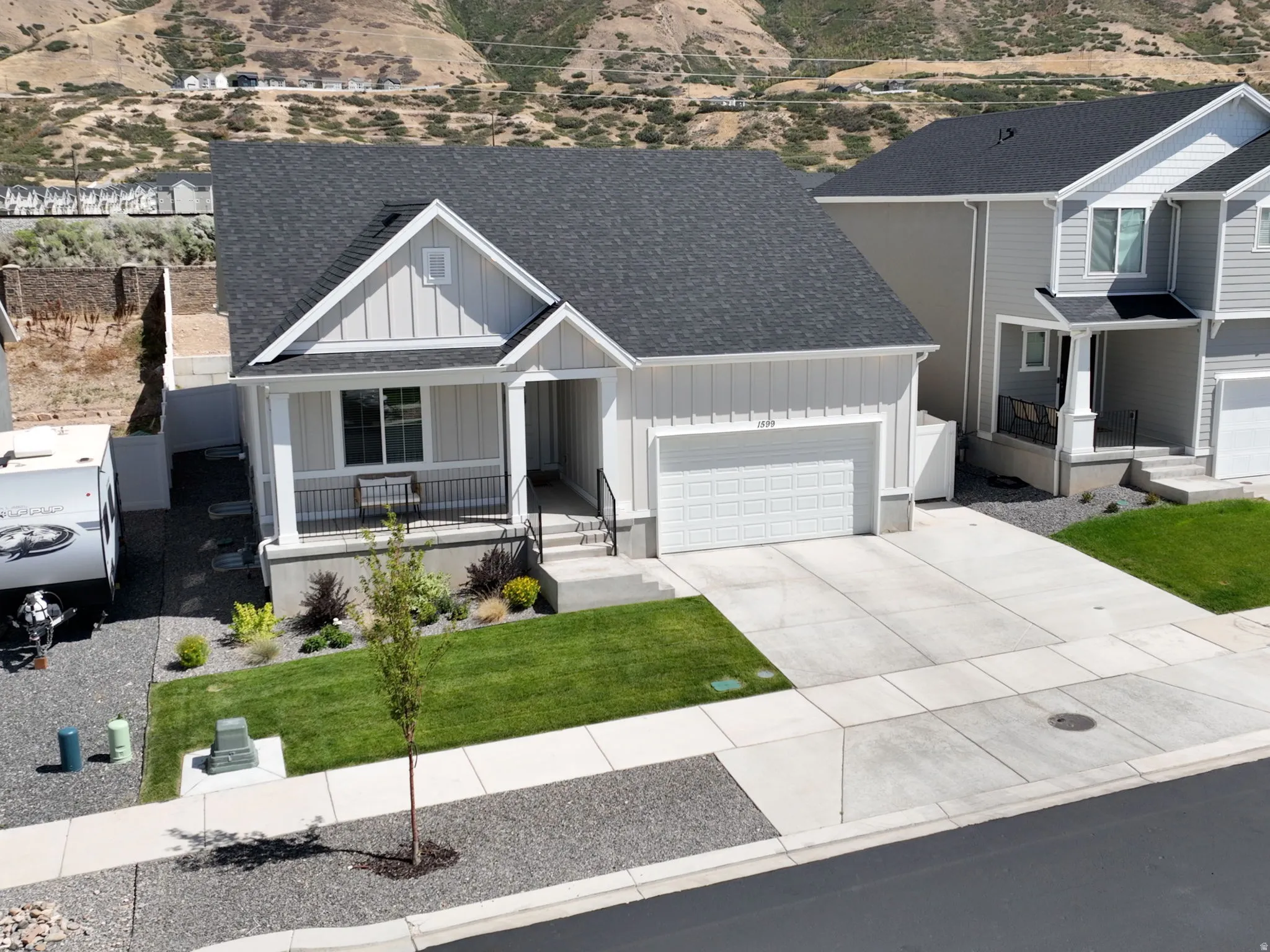 Pitched roof, front porch with columns, attached garage, concrete driveway, and landscaped front yard