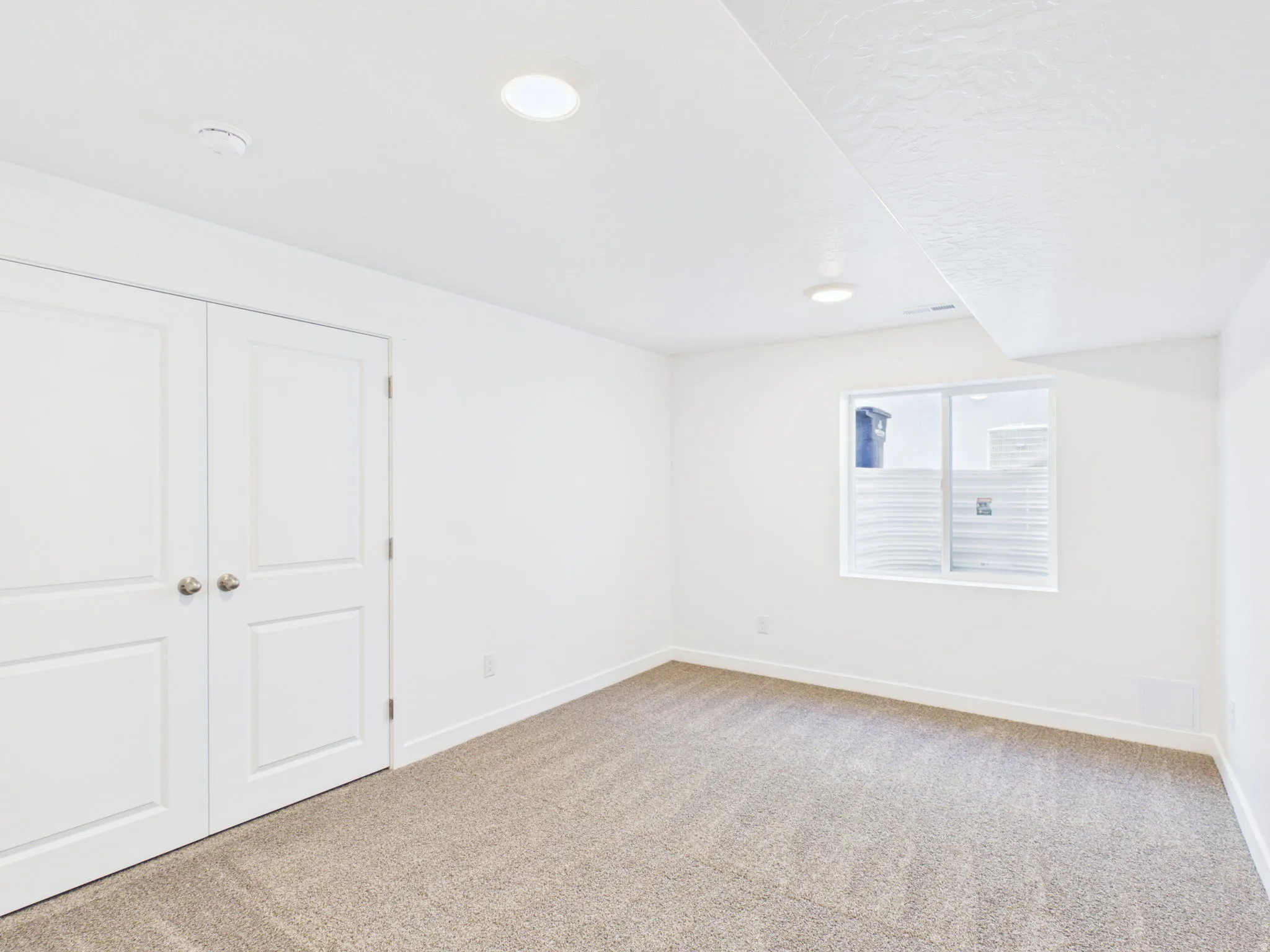 Recessed lighting, carpeted flooring, two-panel interior doors, and a window well