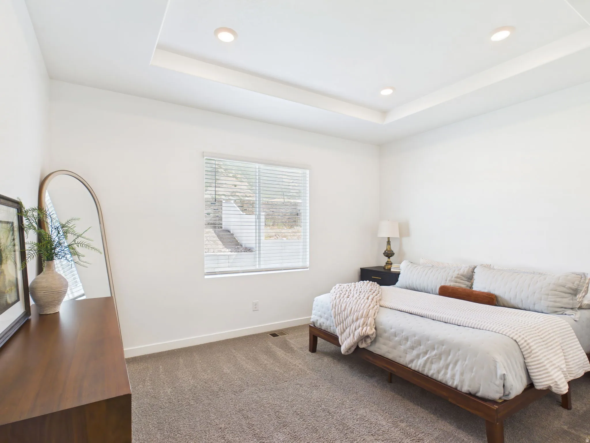 Tray ceiling with recessed lighting, wall-to-wall carpeting, and a window with blinds