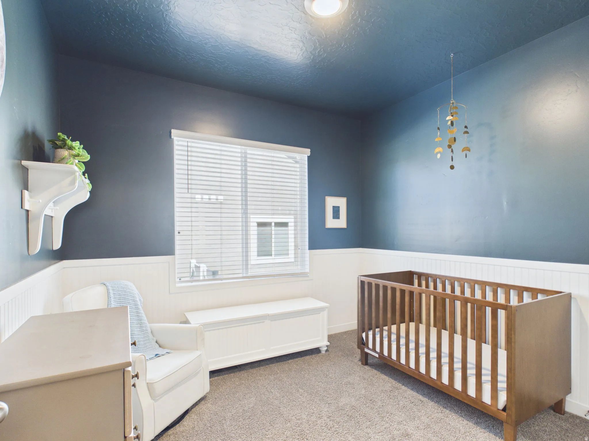 Recessed ceiling light, two-tone wall treatment with wainscoting, window with blinds, and neutral carpet flooring