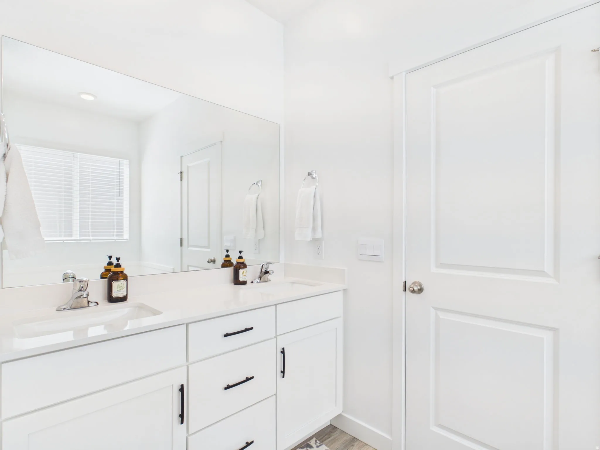 Dual vanity with white cabinetry and integrated sinks, a large frameless mirror, and modern hardware