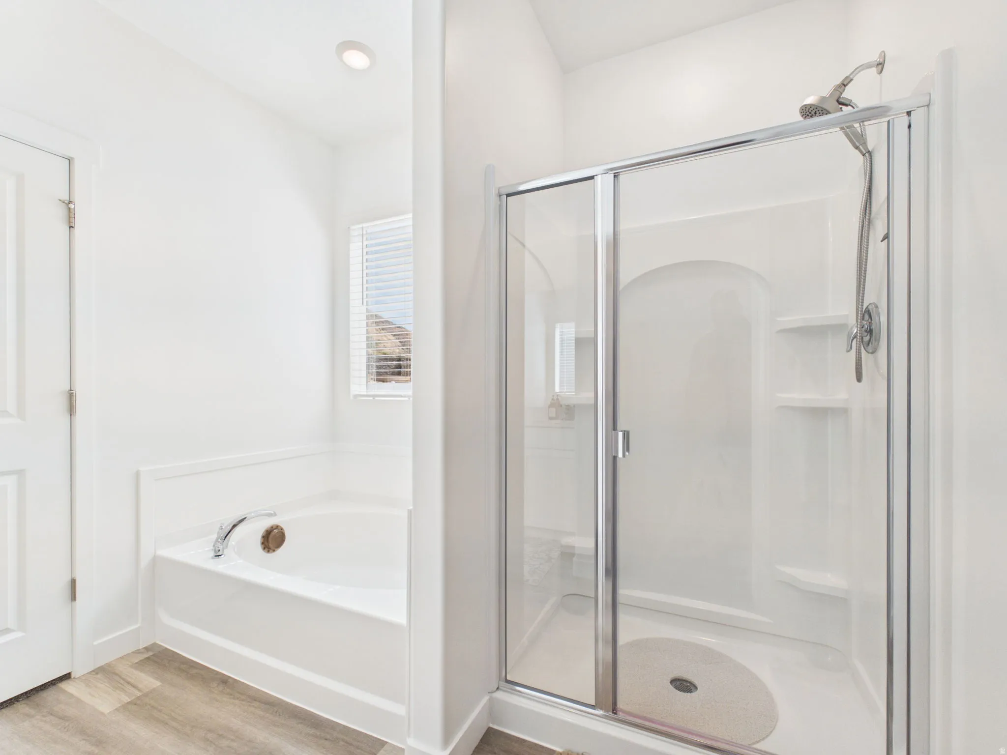 Shower enclosure with clear glass door, built-in shelving, and a handheld showerhead
