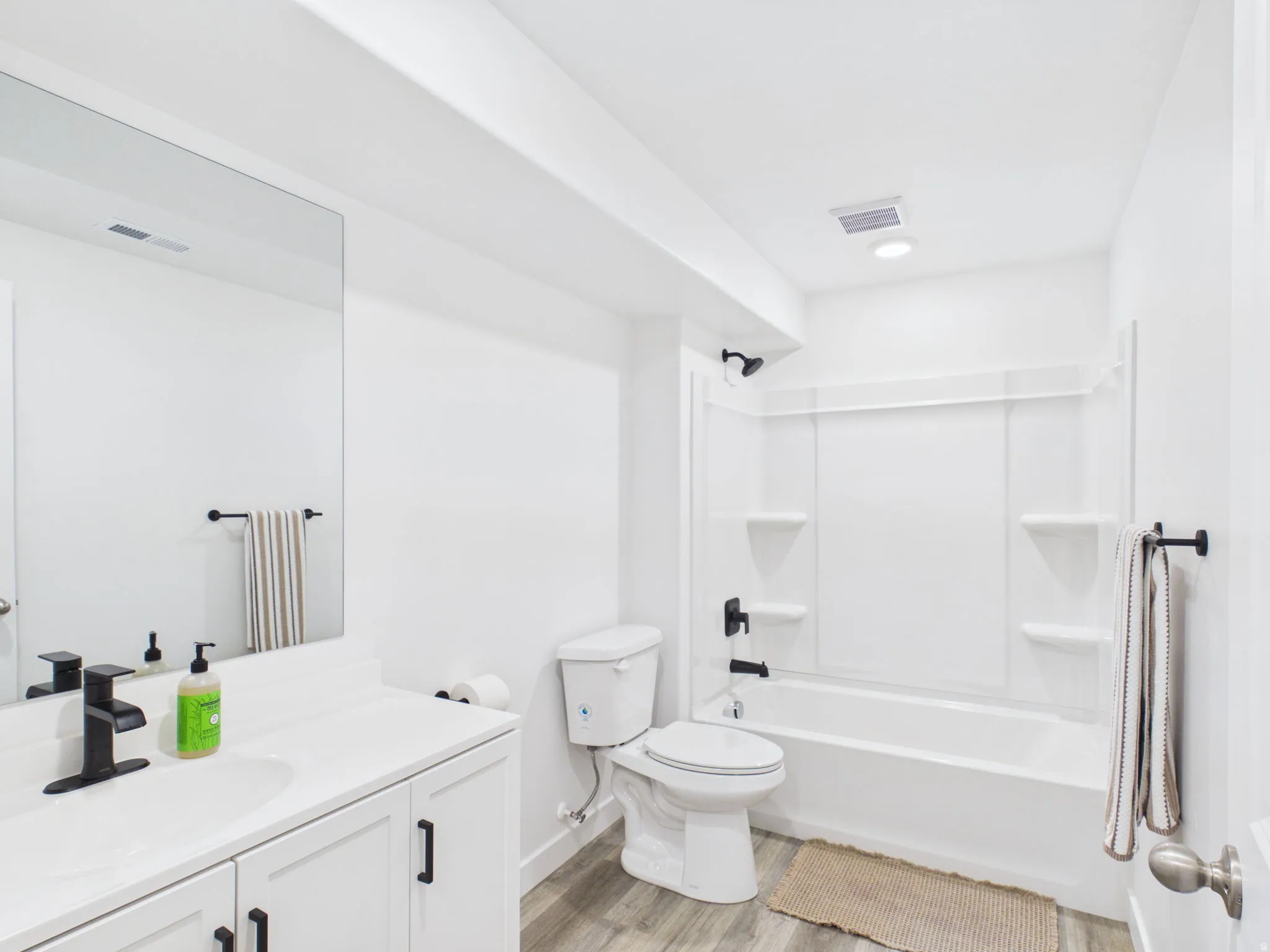 White vanity with a solid surface countertop, matte black faucet, and undermount sink