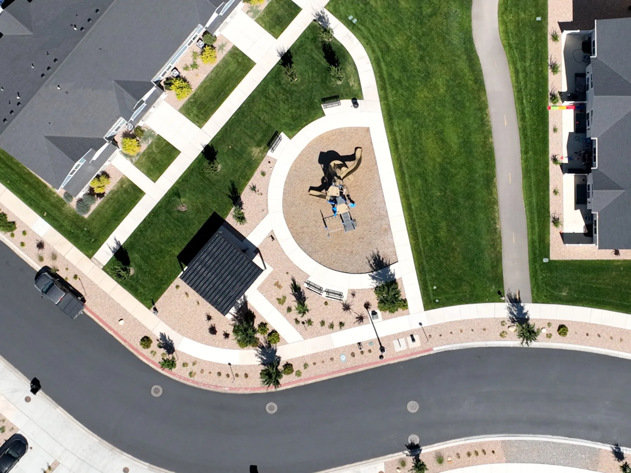 Community green space featuring a playground, walking paths, and shaded seating areas