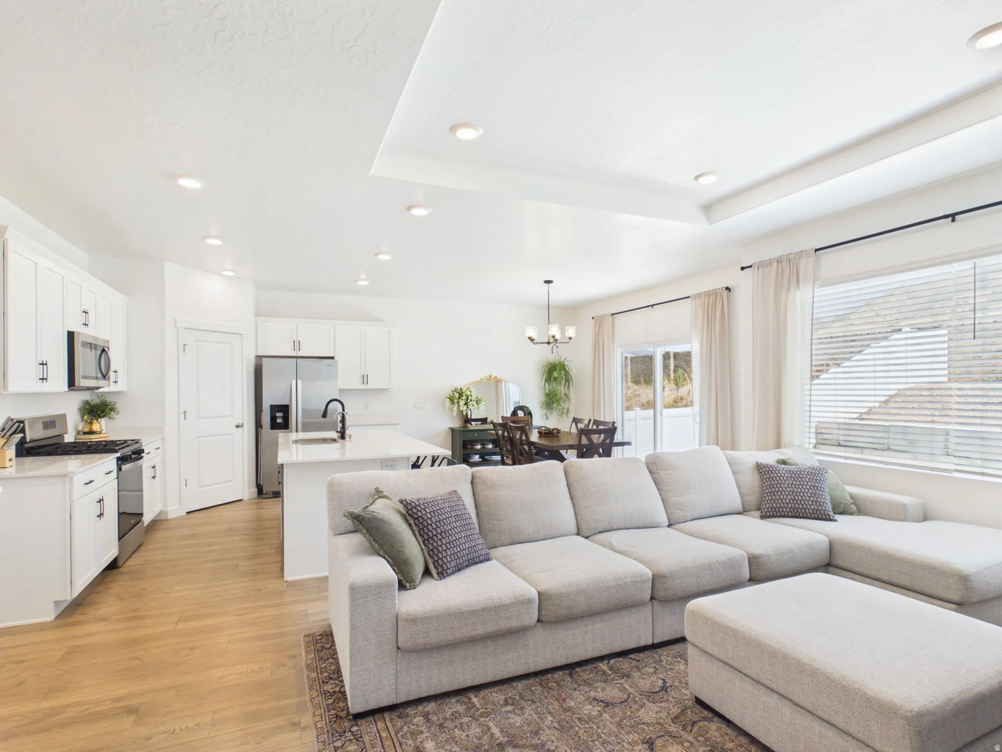 Open-concept living space featuring wood-finish flooring, recessed lighting, and a tray ceiling