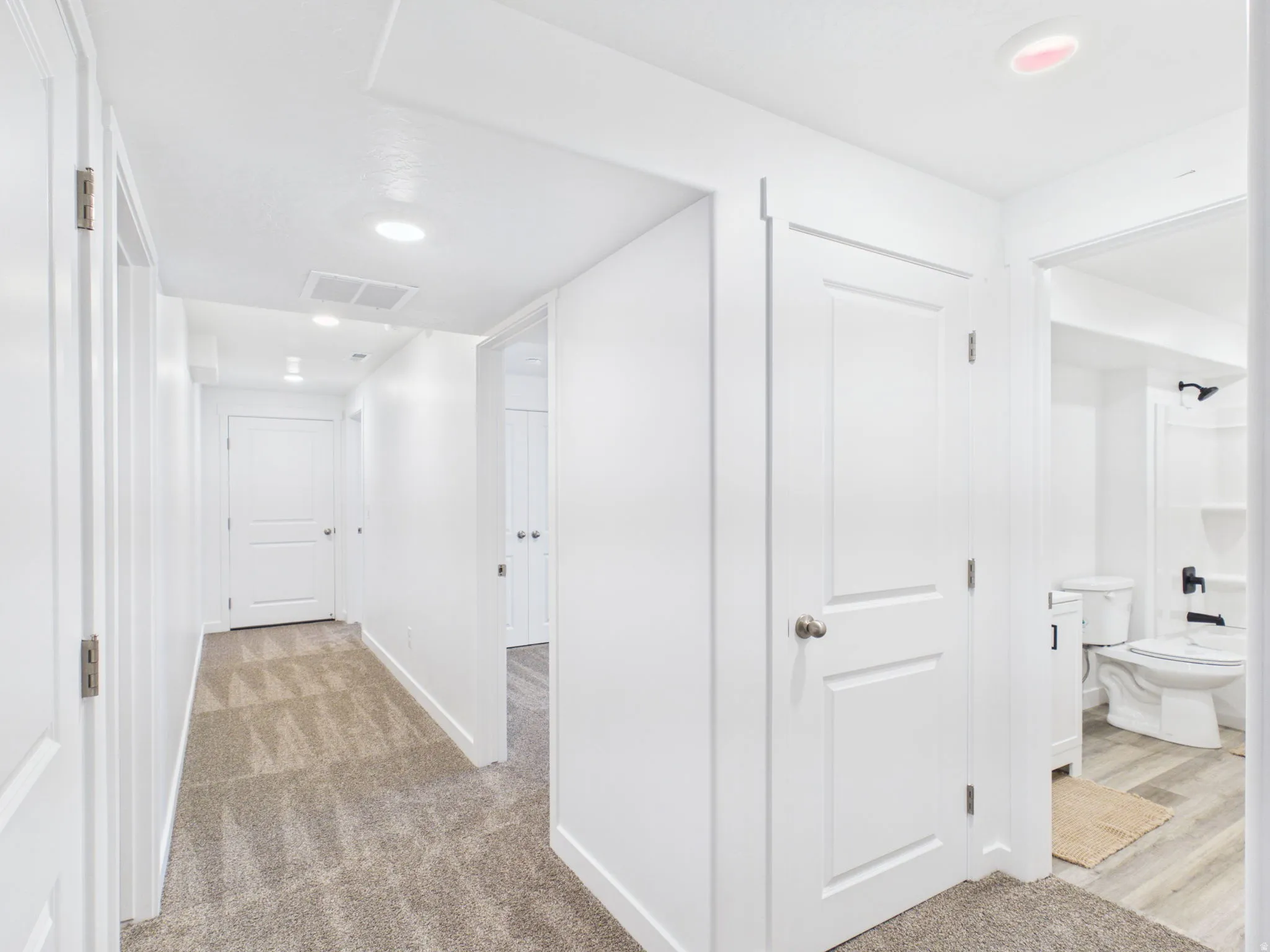 Carpeted hallway with recessed lighting and white panel doors