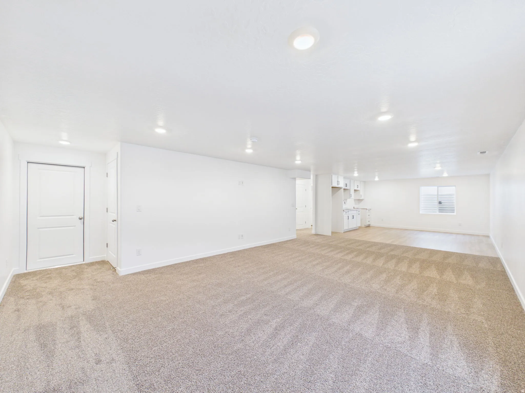 Expansive room featuring recessed lighting, a combination of carpet and wood-finish flooring, white built-in cabinetry, and a window with blinds