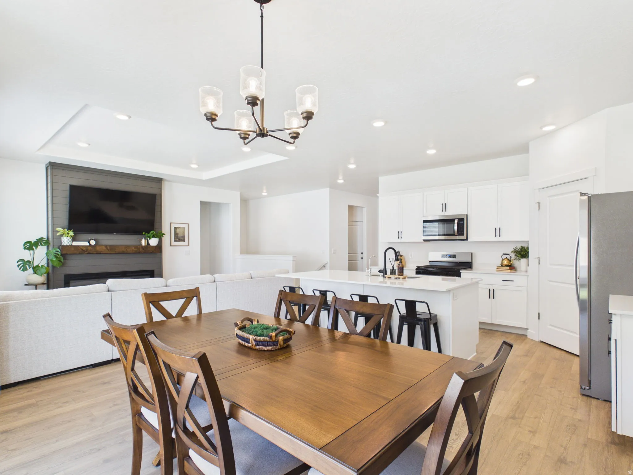 Open-concept living space with wood-finish flooring, recessed lighting, and a tray ceiling