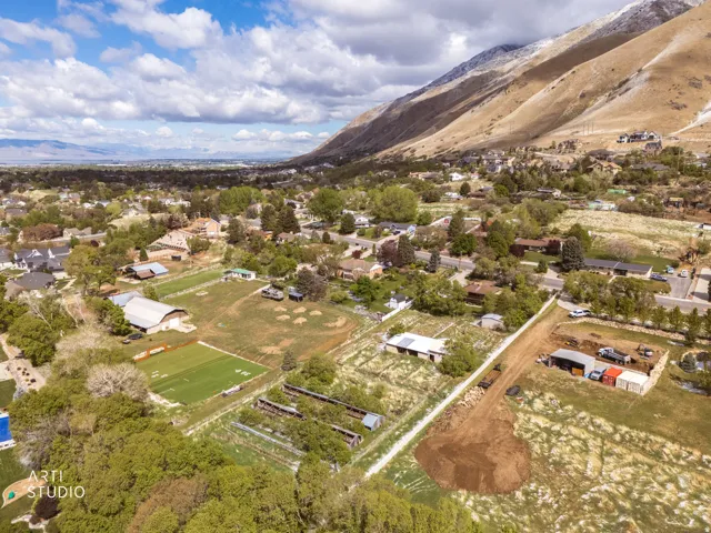 Mountain backdrop, expansive lot, multiple outbuildings, agricultural fields, distant city lights