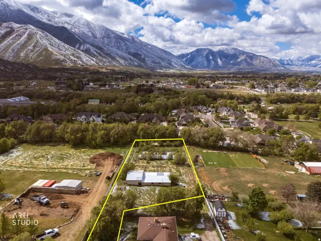 Expansive acreage featuring multiple structures, mature trees, and a mountain backdrop