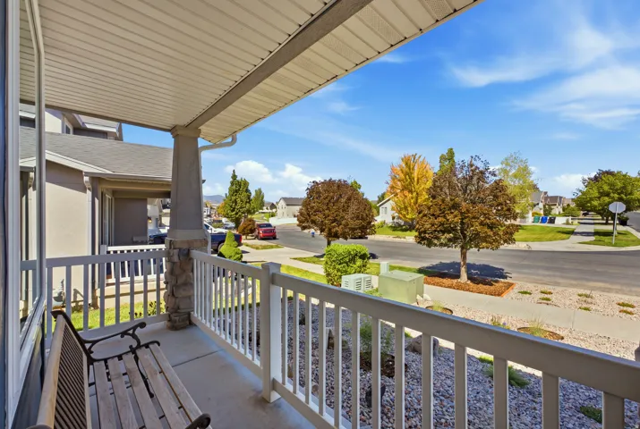 Covered front porch featuring a stone-clad column and white railing