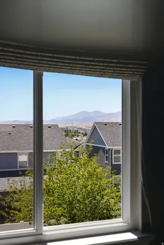 Window with white framing, integrated roller shade, and distant mountain scenery