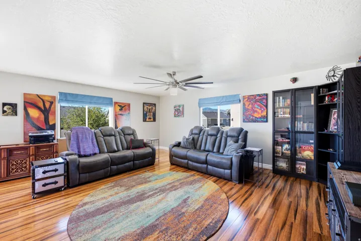 Wood-finish flooring, multiple windows, ceiling fan, built-in shelving, and built-in cabinetry