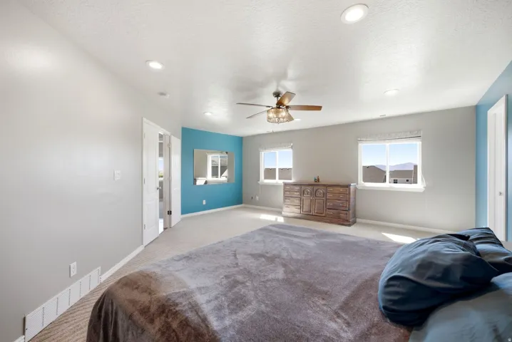 Recessed lighting, ceiling fan, carpeting, two windows, and a partially visible interior door