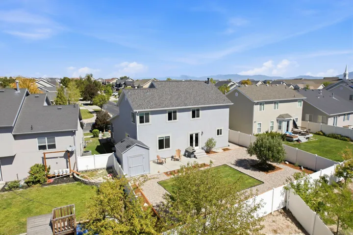 Rear exterior featuring a patio, gravel landscaping, a grass patch, a storage shed, and a privacy fence
