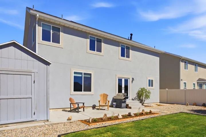 Expansive backyard featuring a manicured lawn, gravel landscaping, and a concrete patio