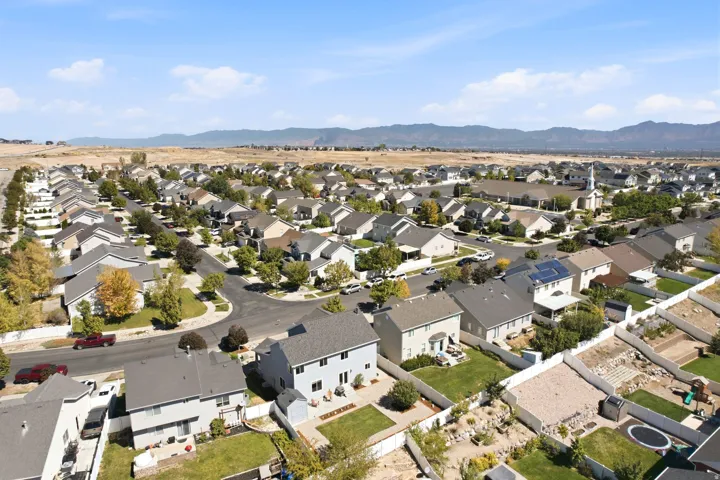 Extensive residential development featuring a variety of single-family homes, mature street trees, and distant mountain scenery