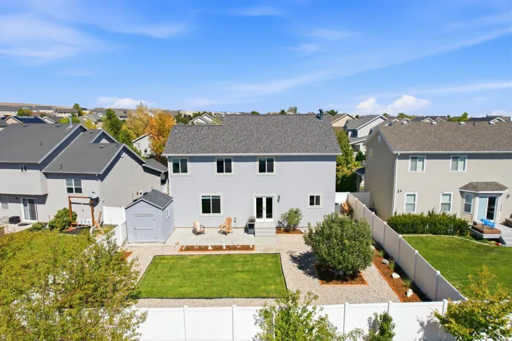 Expansive backyard featuring a manicured lawn, gravel landscaping, and a white privacy fence