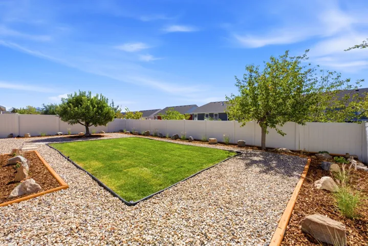Expansive backyard featuring a central lawn area, surrounding gravel pathways, and decorative rock and mulch landscaping
