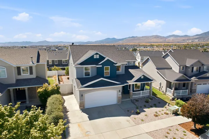 Gable roofline, covered front porch, integrated garage, and a landscaped front yard with decorative rock