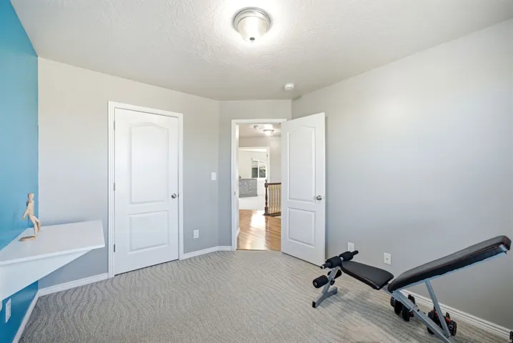 Versatile multi-purpose room featuring neutral wall finishes, recessed ceiling lighting, carpeted flooring, and multiple white six-panel doors providing access to adjoining spaces