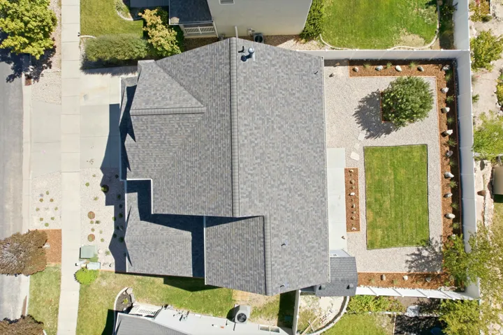 Expansive backyard featuring a manicured lawn, gravel landscaping, and a mature tree