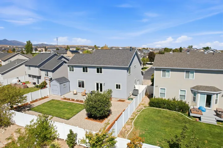 Expansive backyard featuring a central manicured lawn, surrounding gravel landscaping, and a white privacy fence