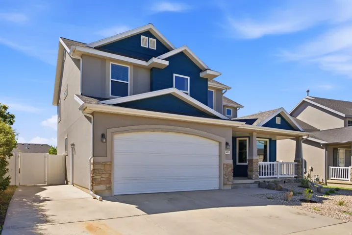 Two-story residence with a stucco and siding exterior, an integrated two-car garage, and a covered front porch featuring white railing