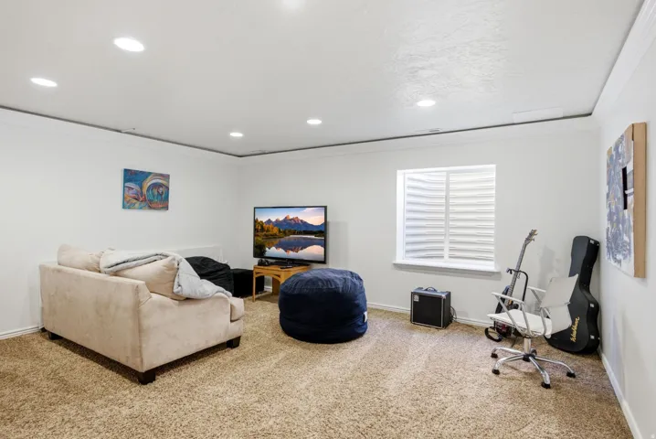 Carpeted room with recessed lighting, crown molding, and a window featuring horizontal blinds
