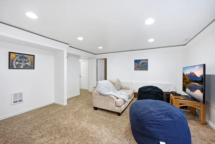 Recessed ceiling lighting, crown molding, white painted walls, and neutral carpet flooring