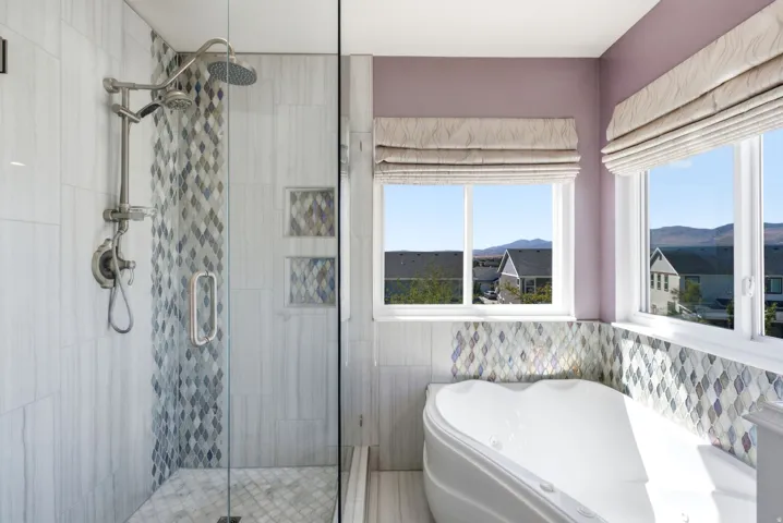 Glass-enclosed shower with multiple showerheads, a built-in jetted tub, and a decorative tile surround