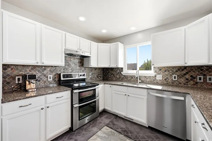 Kitchen featuring white cabinetry, granite countertops, a stainless steel double oven, a stainless steel dishwasher, and mosaic tile backsplash