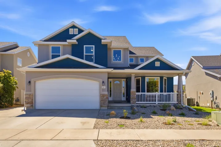 Two-story residence with a covered front porch featuring white railing, an attached two-car garage, and a concrete driveway