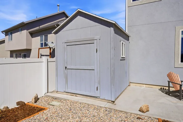 Storage shed with a single window, built on a concrete slab, featuring a privacy fence