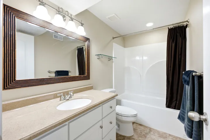 White vanity with ample storage, a single basin sink, and a light-toned countertop