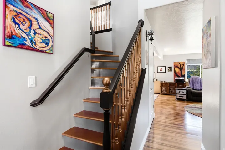 Staircase featuring wood treads, painted risers, and a wrought iron and wood-finish banister