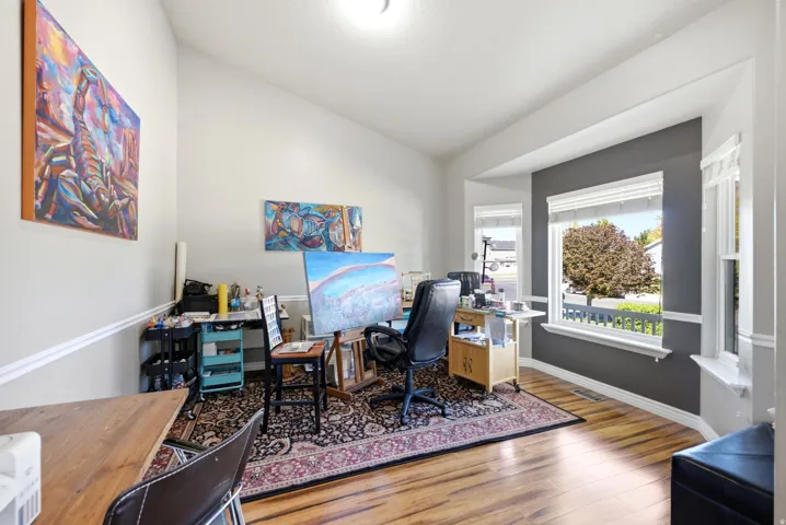 Vaulted ceilings, wood-finish flooring, and a large bay window with white trim