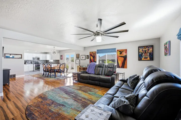 Open-concept living area with wood-finish flooring, a contemporary ceiling fan, and light gray walls