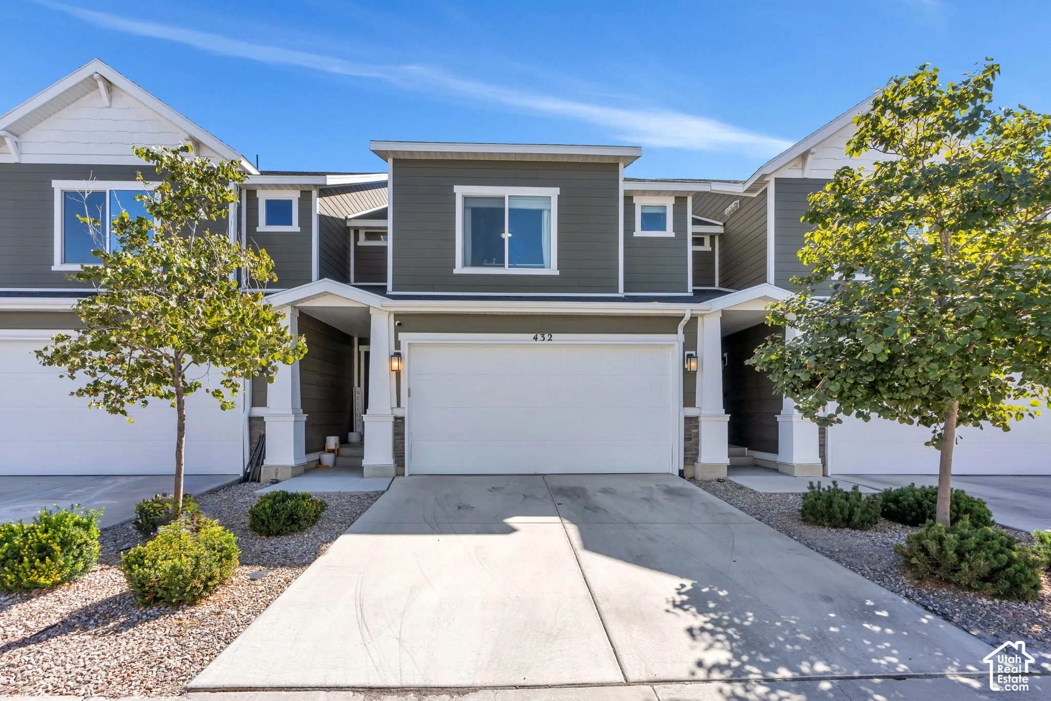 Multi-story exterior with horizontal siding, a prominent garage, a covered entryway, and mature landscaping