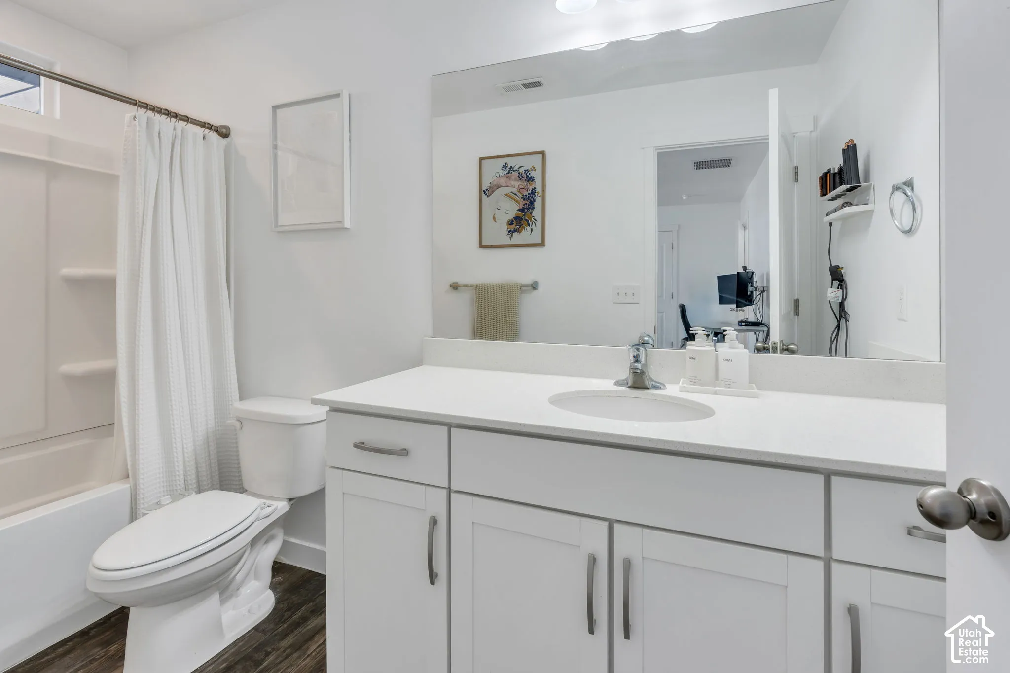 White vanity with integrated sink, chrome faucet, and expansive mirror