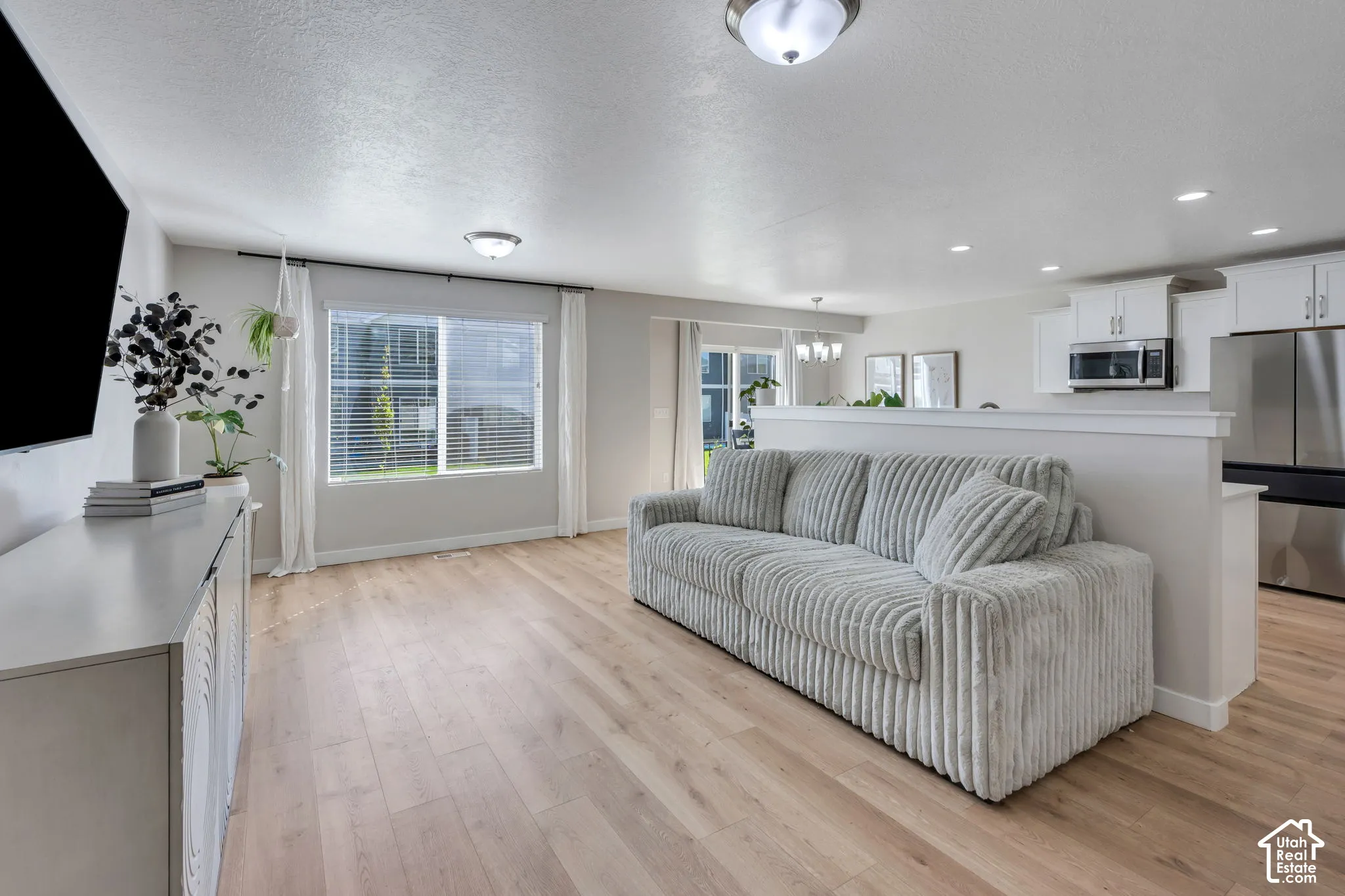 Open-concept living area featuring wood-finish flooring, recessed lighting, and a kitchen with stainless steel appliances