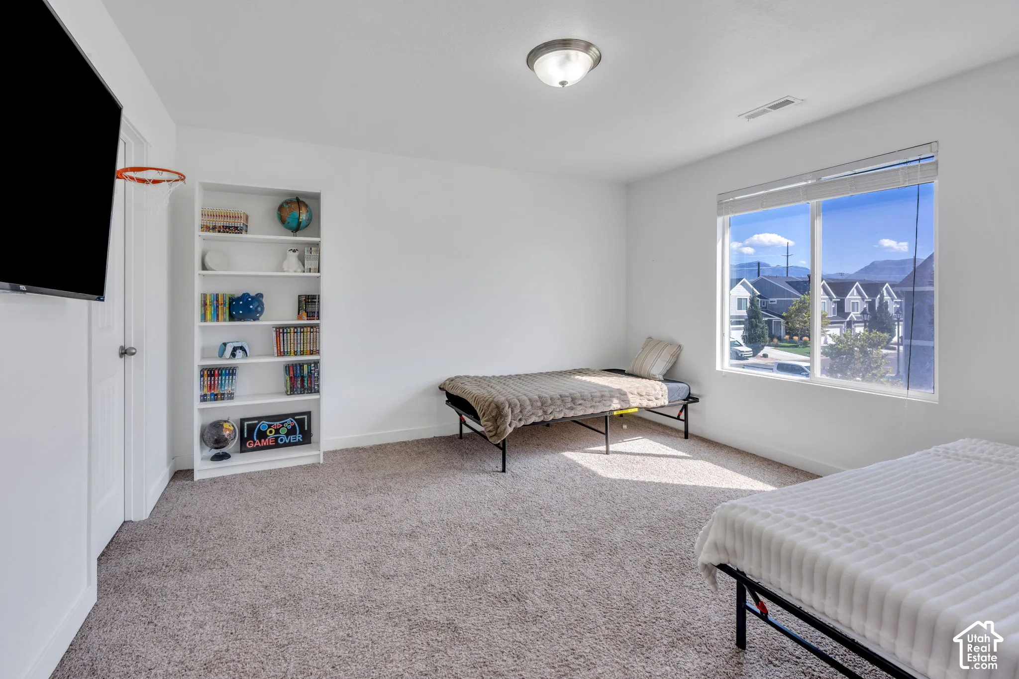 Neutral carpet flooring, built-in shelving unit, and a large window with blinds