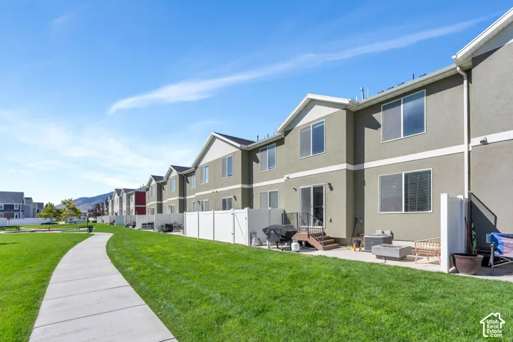 Expansive green space with a concrete pathway, private patio, and sliding glass door access